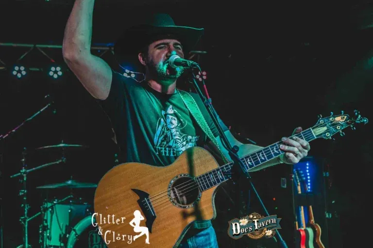 Chad Bushnell of Thunder Rolls singing with acoustic guitar and one arm raised on stage