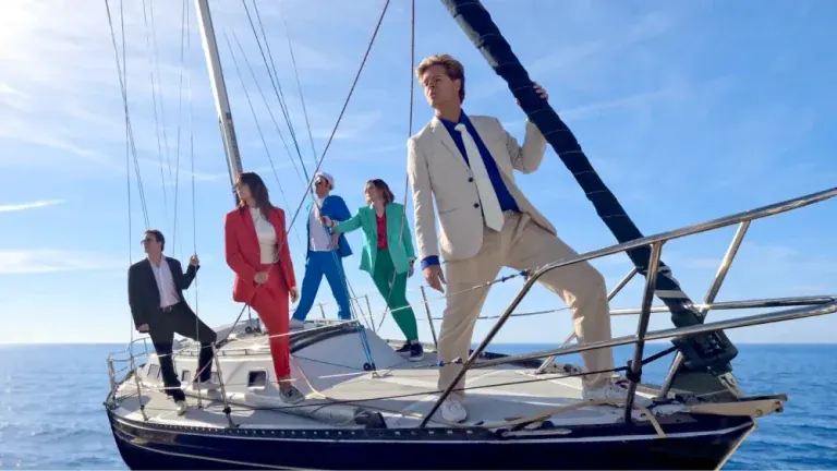 New Moon on Monday Duran Duran tribute band posing in colorful suits on the bow of a sailboat