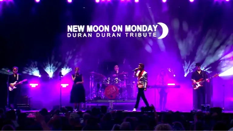 New Moon on Monday Duran Duran tribute performing on a stage lit in purple with the band's logo overhead